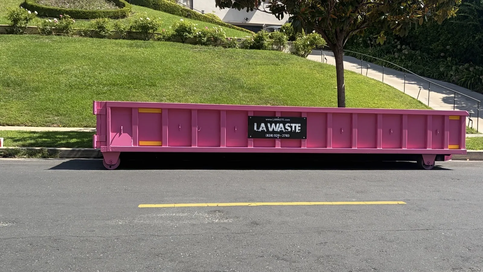 Pink LA Waste 10 yard low boy dumpster placed curbside at a home