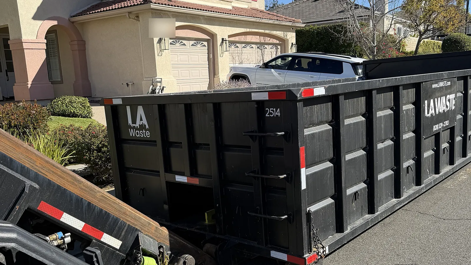 LA Waste 25 yard dumpster being dropped in front of a home