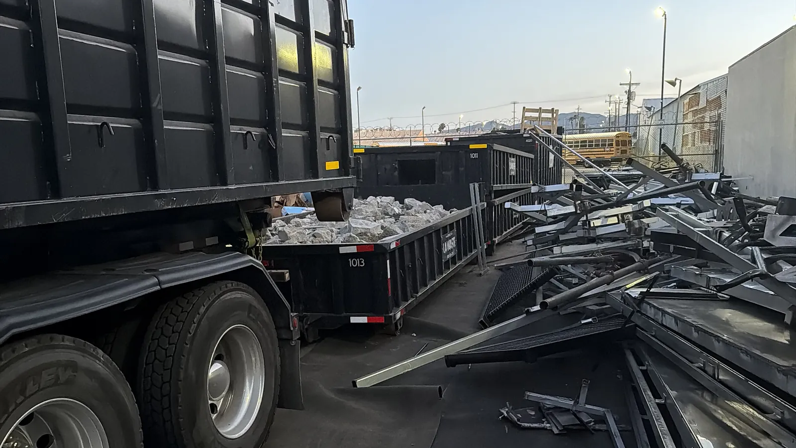 LA Waste roll off truck beside a low boy dumpster loaded with concrete